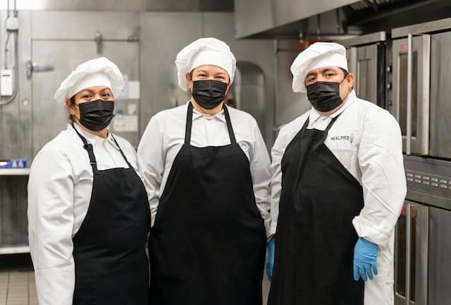 three kitchen workers in clean uniforms